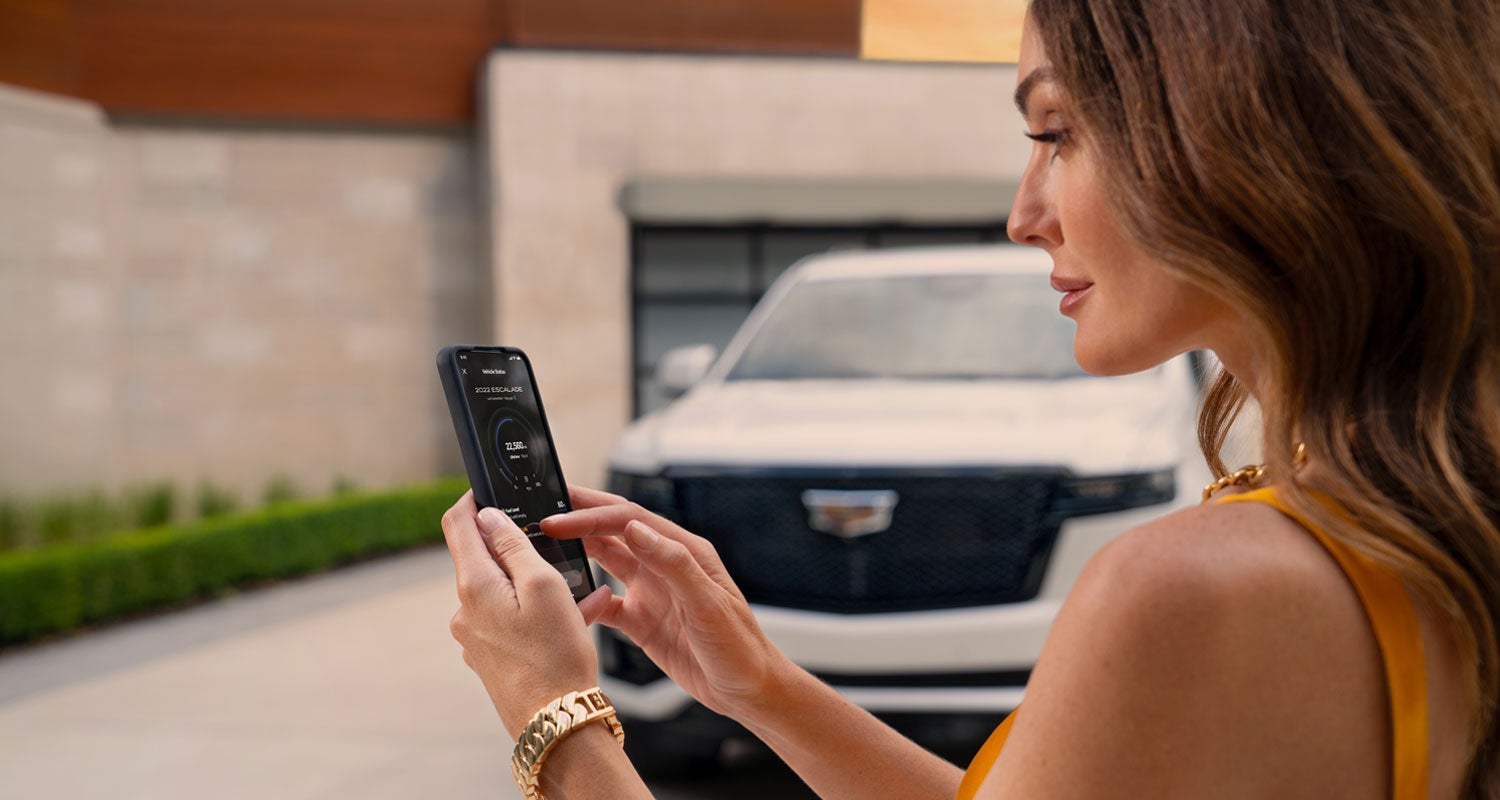 lady checking her mobile with a Cadillac vehicle background | Brogan Cadillac of Totowa in Totowa NJ